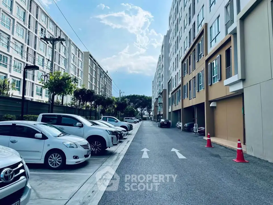 Modern apartment complex with spacious parking area and clear sky view.