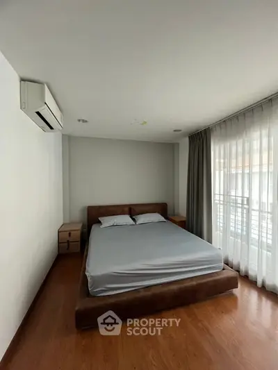 Modern bedroom with minimalist design and natural light from large window.
