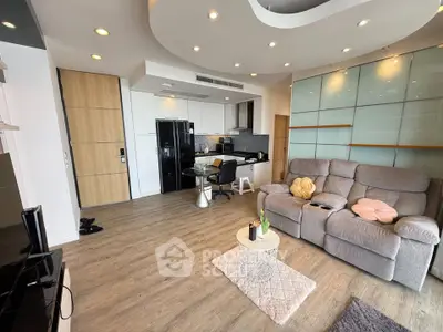 Modern living room with open kitchen, stylish decor, and cozy seating area in a contemporary apartment.