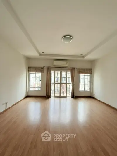 Spacious empty living room with wooden flooring and large windows
