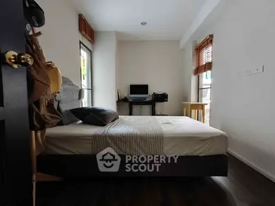 Cozy bedroom with natural light and workspace, ideal for modern living.