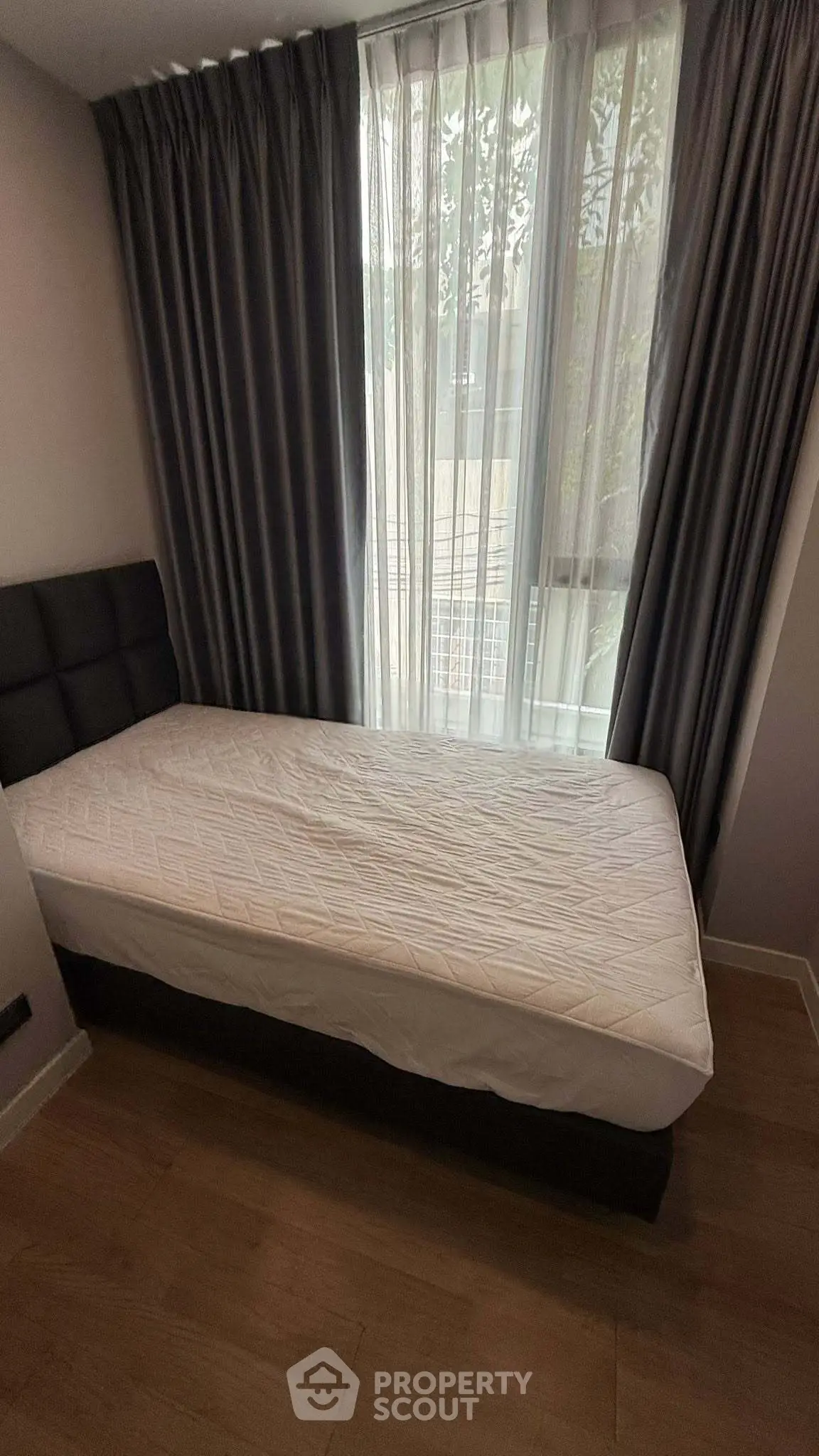 Cozy bedroom with single bed and floor-to-ceiling window with curtains, perfect for natural light lovers.