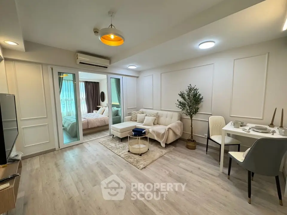 Modern living room with elegant decor and open layout leading to a cozy bedroom.