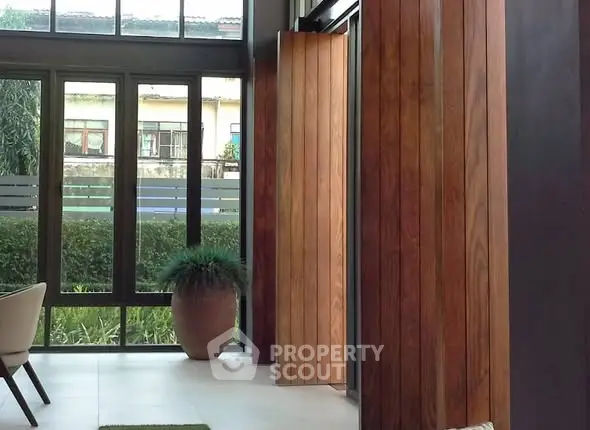 Modern interior with large windows and wooden paneling, featuring a potted plant and sleek design.