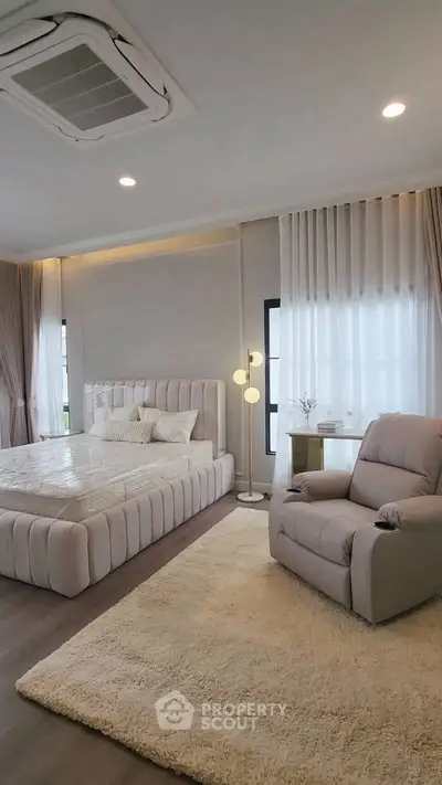 Luxurious bedroom with plush bed, cozy recliner, and elegant decor