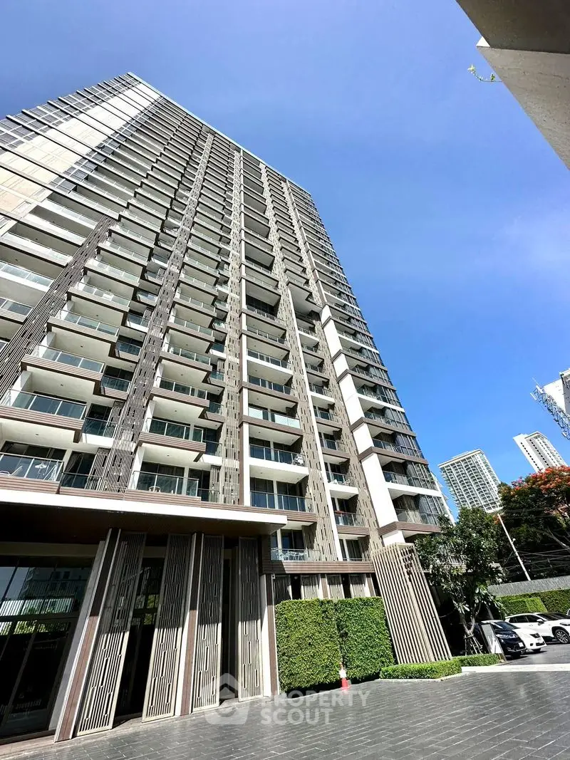 Stunning modern high-rise building with sleek design and spacious balconies in urban setting.