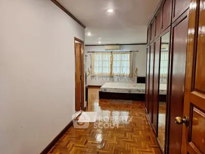 Spacious bedroom with wooden flooring and large windows for natural light.