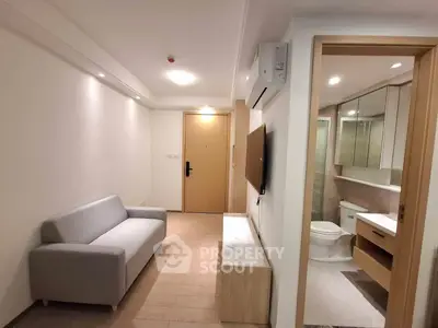 Modern apartment interior with cozy living room and adjacent bathroom, featuring sleek design and neutral tones.