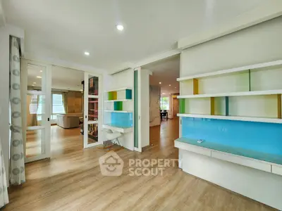 Spacious modern living area with colorful shelving and wooden flooring