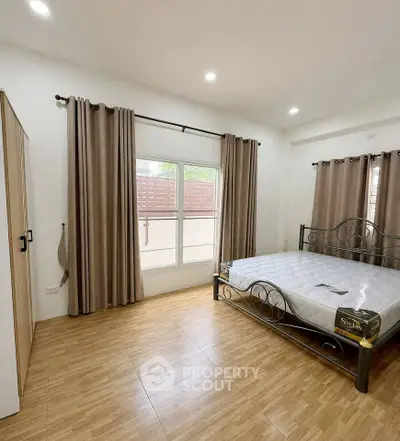 Spacious bedroom with elegant metal bed frame and large window for natural light.