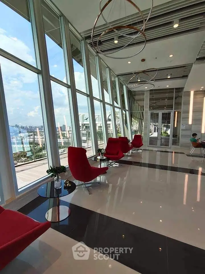 Luxurious modern building lobby with panoramic windows and stylish red chairs.