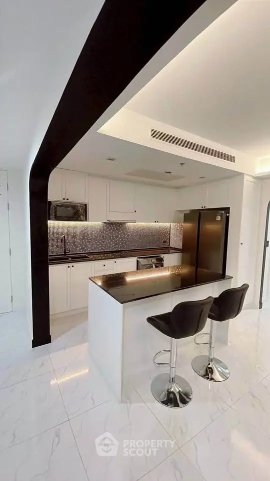 Modern kitchen with sleek black and white design, featuring an island and stylish bar stools.