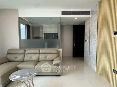 Modern living room with sleek leather sofa and marble accents, featuring an open layout and contemporary design.