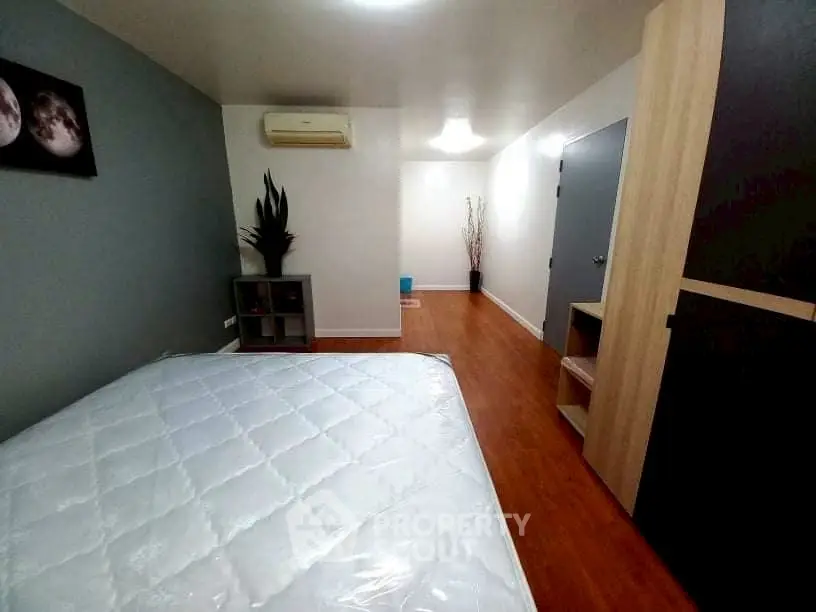 Spacious bedroom with modern decor and wooden flooring, featuring a comfortable bed and ample storage space.
