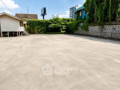 Spacious outdoor area with potential for development, featuring lush greenery and privacy walls.