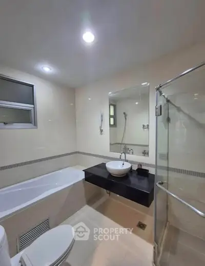Modern bathroom with bathtub and glass shower enclosure in a sleek, minimalist design.