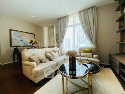 Luxurious living room with elegant decor and large window, featuring plush seating and stylish accents.