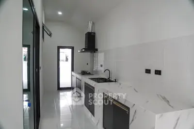 Sleek modern kitchen with marble countertops and gas stove in a bright, minimalist design.