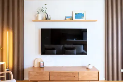 Modern living room with sleek wooden furniture and wall-mounted TV, perfect for stylish urban living.