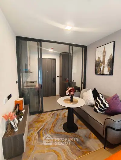 Stylish modern living room with cozy sofa, chic decor, and elegant glass partition leading to kitchen.