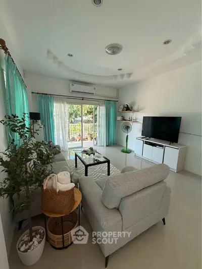 Spacious living room with modern decor and large windows offering natural light and garden view.