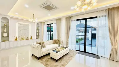 Luxurious living room with elegant decor and large windows offering natural light and garden view.