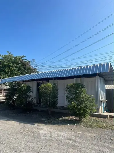 Charming small house with metal roof and lush greenery, perfect for cozy living or investment opportunity.