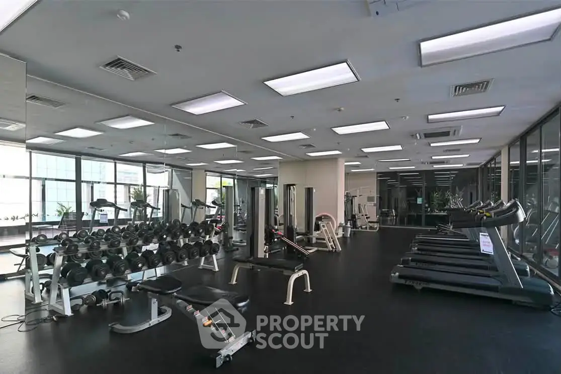 Spacious modern gym with state-of-the-art equipment and large windows for natural light.