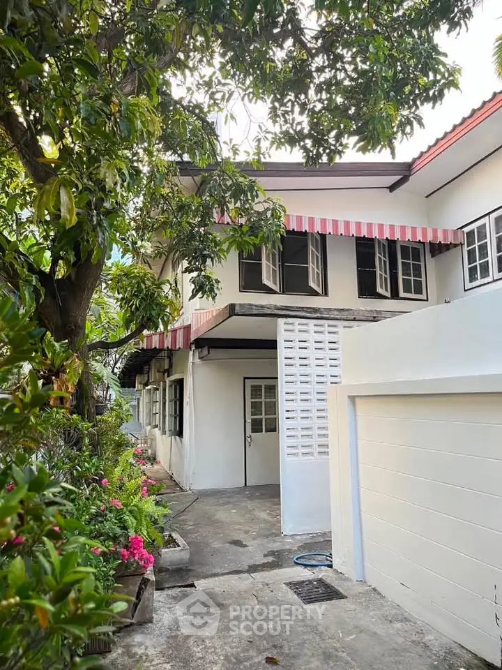 Charming two-story house with lush garden and classic awnings, perfect for family living.
