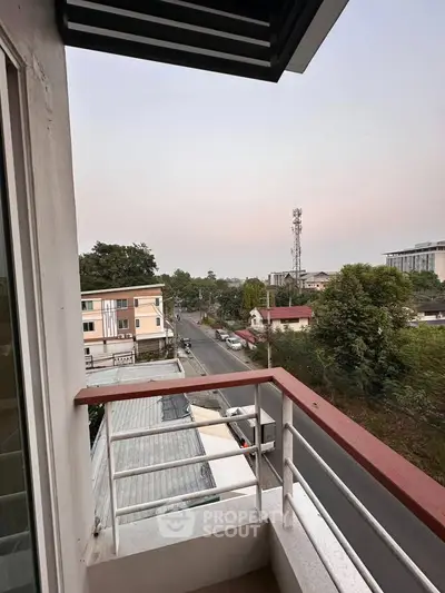 Charming balcony view overlooking a serene neighborhood street and lush greenery.