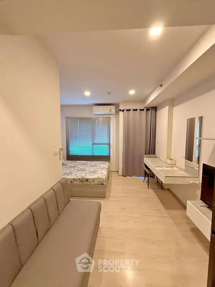 Modern studio apartment with cozy bed, stylish sofa, and sleek desk in open layout.