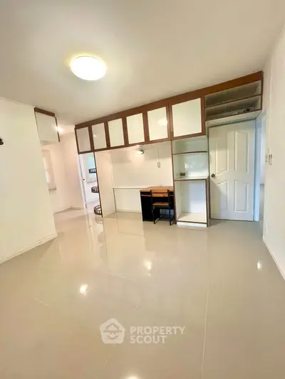 Spacious modern living area with glossy tiled floors and built-in storage, perfect for urban living.