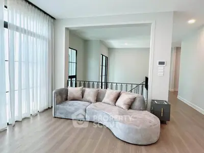 Modern living room with stylish curved sofa and large windows for natural light.