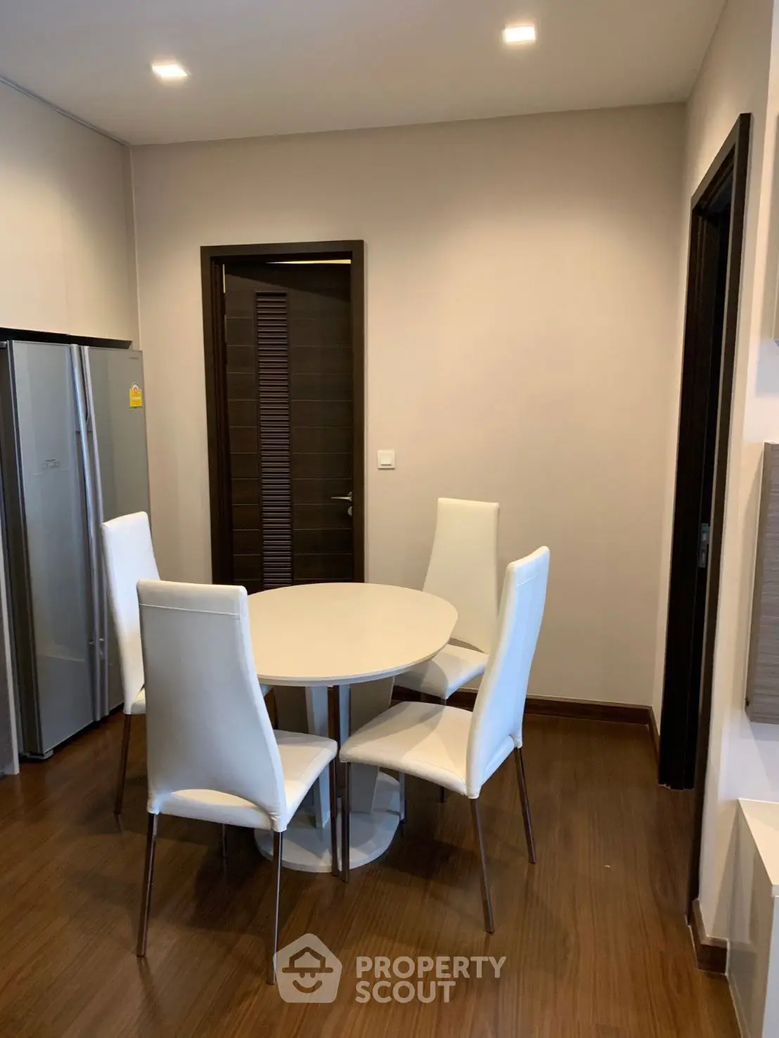 Modern dining area with sleek white chairs and round table in stylish apartment.