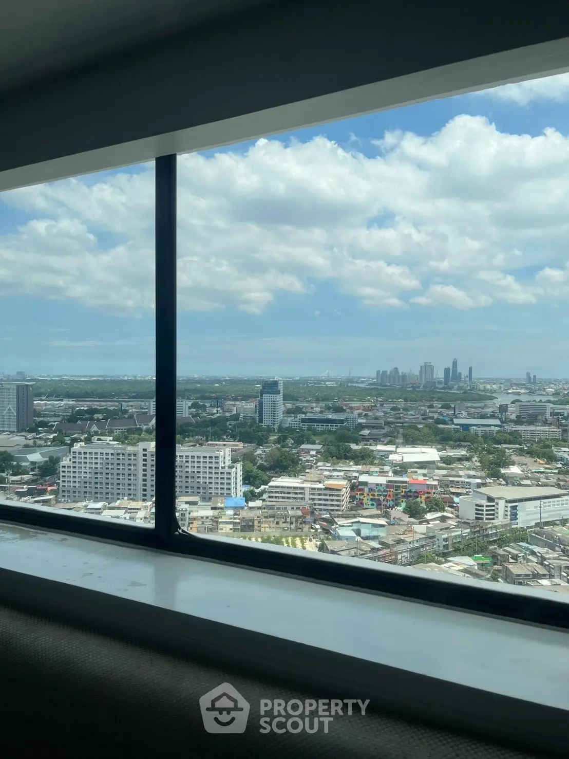 Stunning cityscape view from a high-rise window, showcasing urban skyline and blue skies.