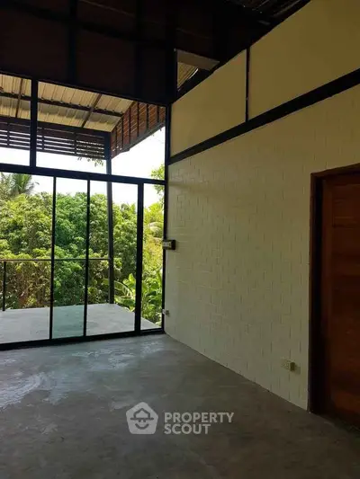 Spacious room with large windows and lush garden view, perfect for modern living.