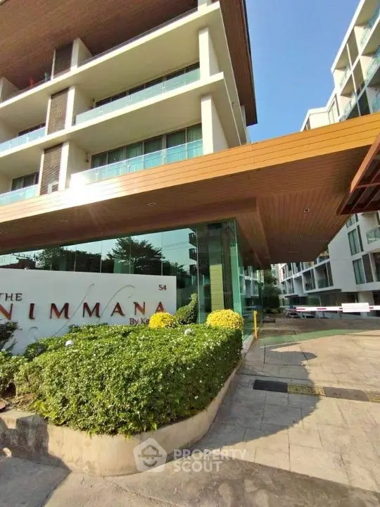 Modern condominium entrance with sleek architecture and lush greenery.