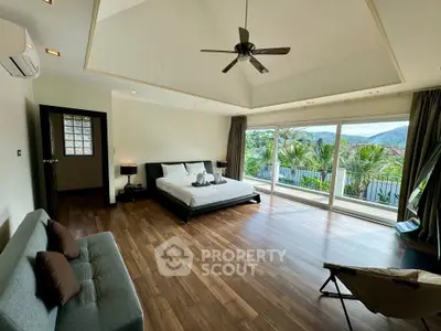Spacious bedroom with large windows and scenic view, featuring modern decor and wooden flooring.