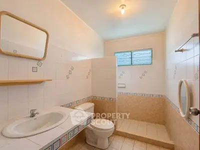 Spacious bathroom with tiled walls and modern fixtures in a well-lit setting.