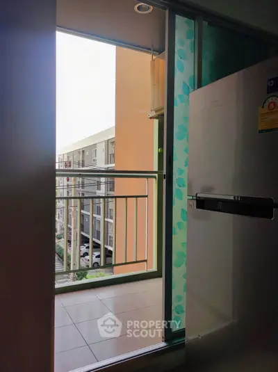 Modern apartment balcony with sliding glass door and view of neighboring building.