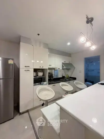 Modern kitchen with sleek white cabinets and breakfast bar in a stylish apartment.