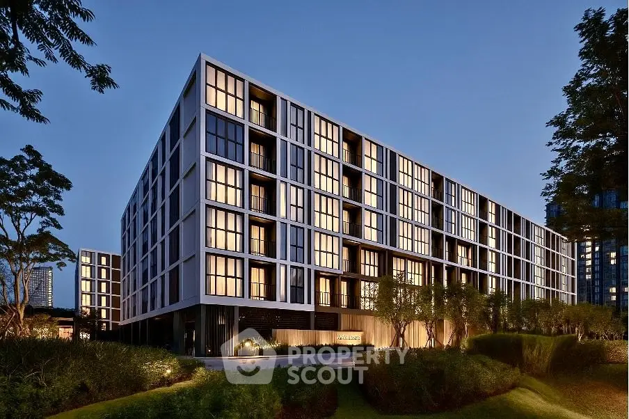 Modern apartment building with sleek design and illuminated windows at dusk.