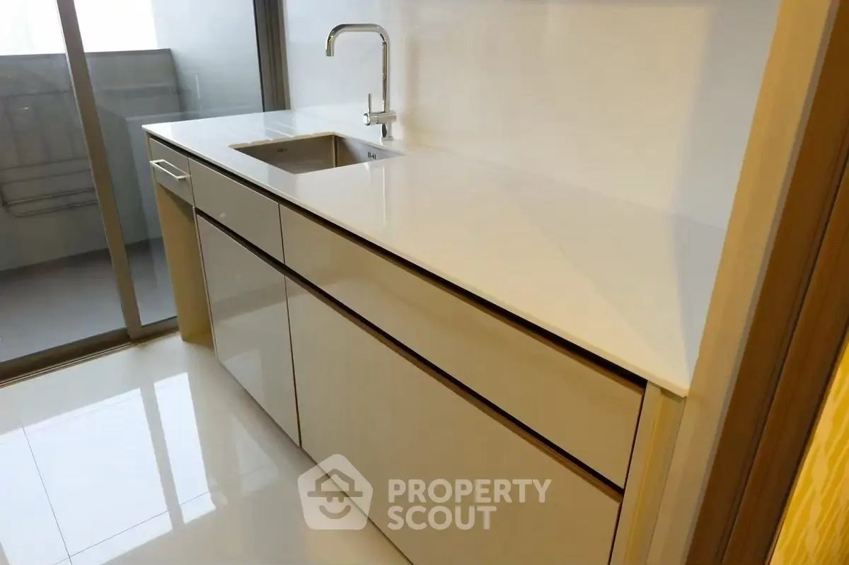 Modern kitchen with sleek cabinetry and built-in sink, featuring glossy countertops.