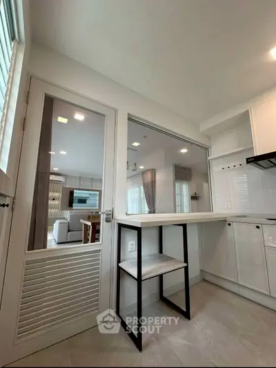 Modern kitchen with open layout and sleek design, featuring a breakfast bar and view into living area.