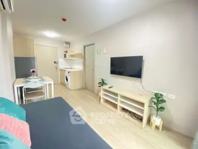 Modern living room with open kitchen, featuring sleek furniture and a wall-mounted TV.