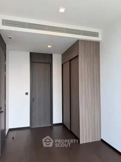 Modern minimalist bedroom with sleek wooden flooring and built-in closet