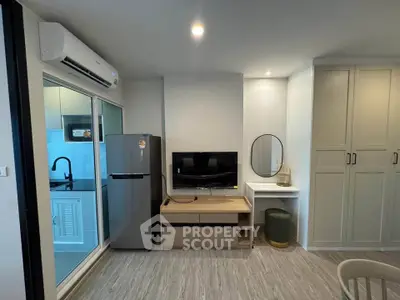 Modern living room with sleek furniture and integrated kitchen area, featuring a stylish fridge and air conditioning.