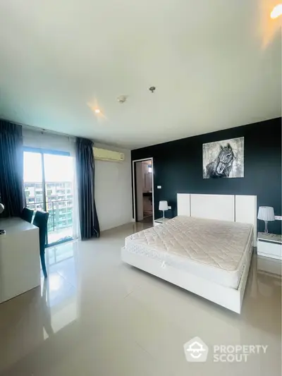 Spacious modern bedroom with large window and sleek furnishings in a high-rise apartment.