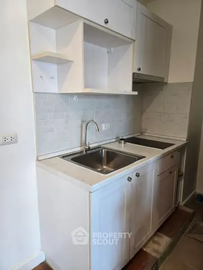Modern kitchen with sleek cabinetry and stainless steel sink in a compact layout.
