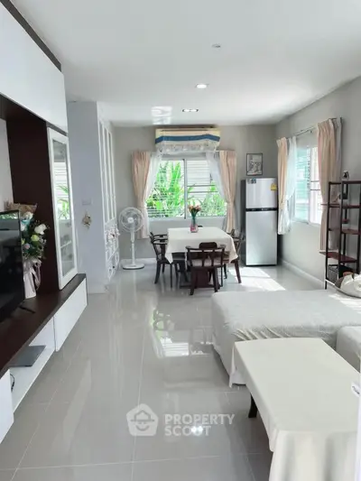 Spacious living room with modern decor and dining area, featuring large windows and natural light.